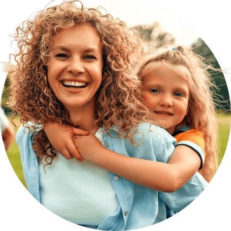 Smiling mother with young daughter outdoors, representing affordable family health insurance coverage including pediatric care
